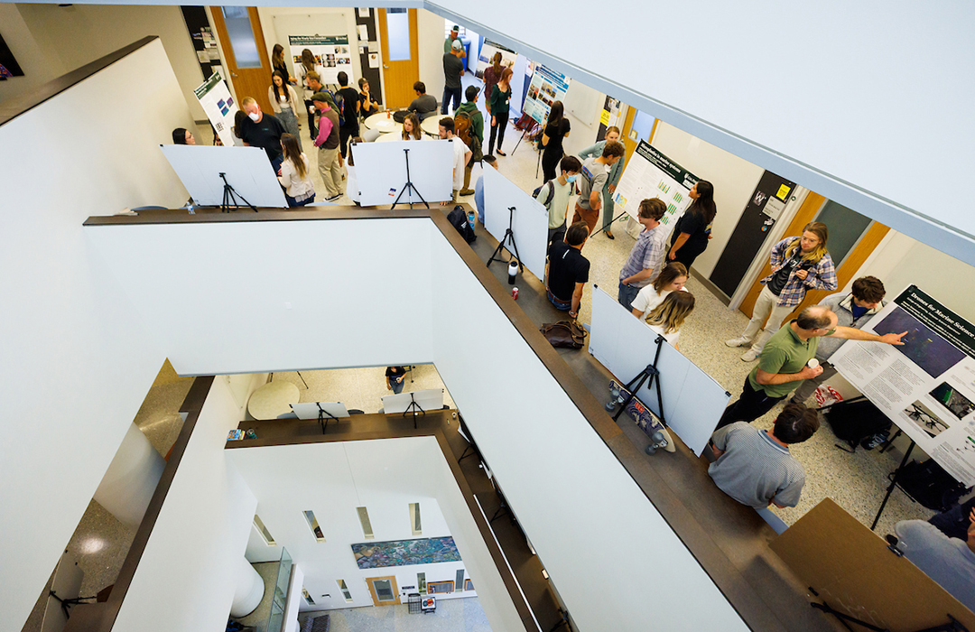 Attendees gather around student poster presentations during the Bailey College Student Research Conference