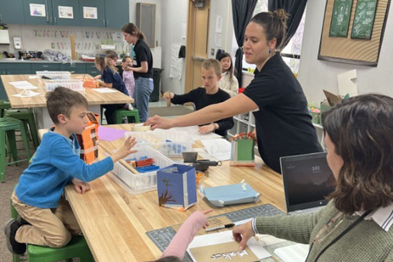Cal Poly student mentor helps an elementary school student assemble a cardboard toolkit during an after-school STEM Maker’s Club activity.