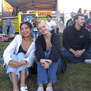 Students in the Frost Summer Undergraduate Research Program sitting on the grass at a San Luis Obispo Blues baseball game during a networking event.