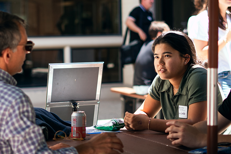 Cal Poly student sitting at a table with an alumnus at an outdoor mentorship event. 
