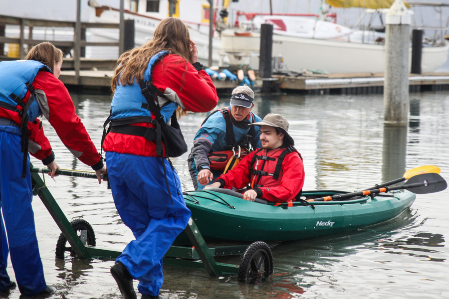 AAP support team helping a participant in a kayak into the water.