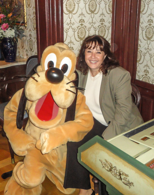 Sherri Brown stands beside Pluto, the yellow Disney dog character, at a company event.