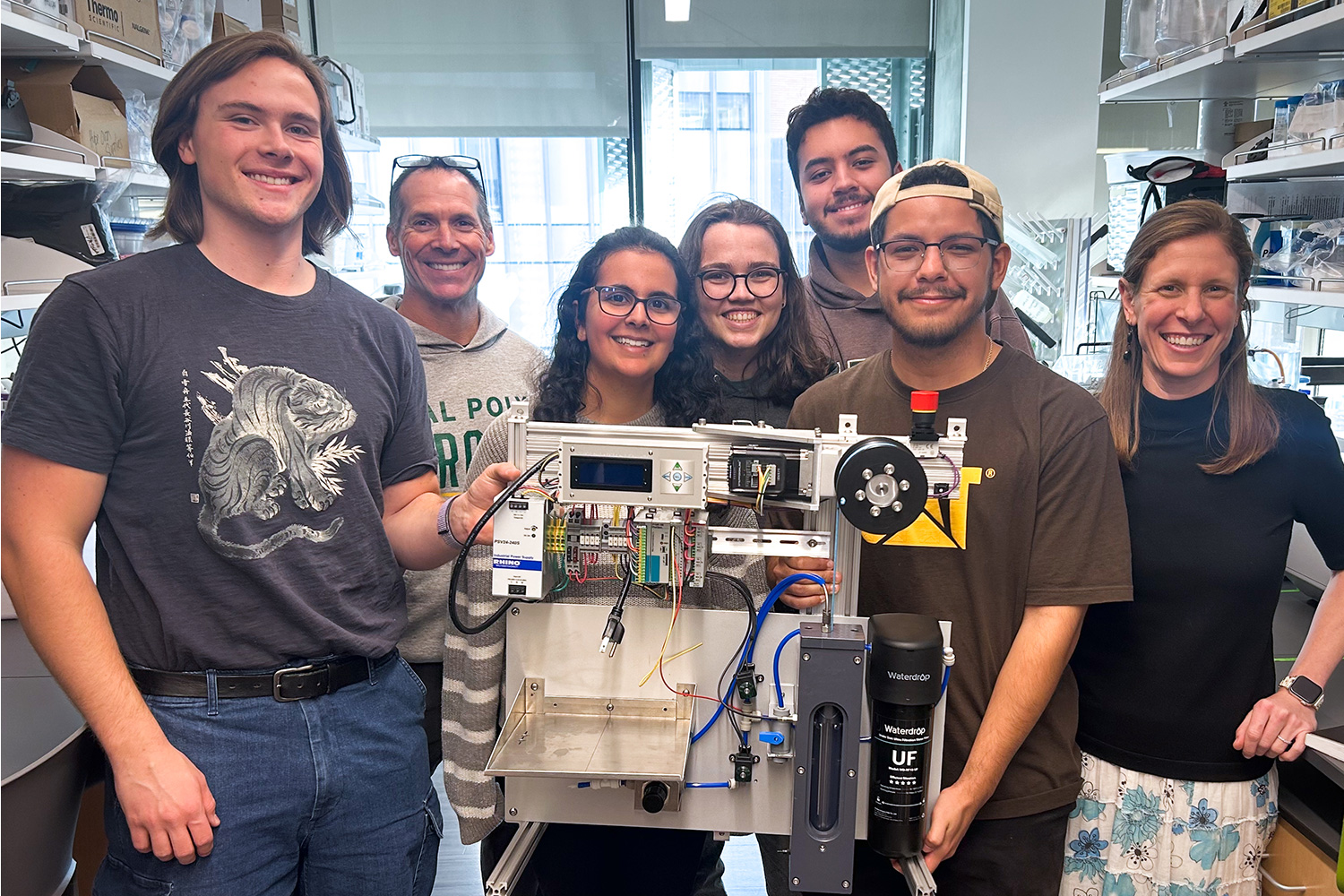 Research group holding equipment in lab.