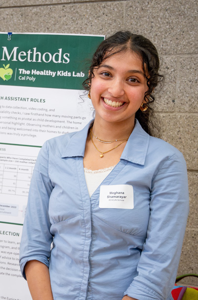 Meghana Shamarayar posing in front of a research poster
