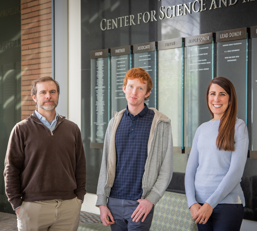 Three Cal Poly researchers of infant health stand together indoors in front of a wall displaying donor recognition panels, posing for a group photo.stand together indoors in front of a wall displaying donor recognition panels, posing for a group photo.