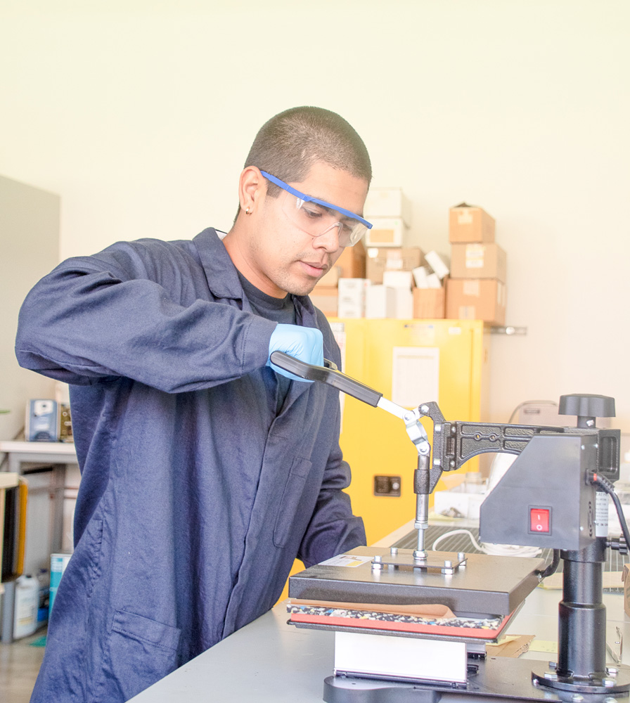 Cal Poly chemistry student researcher works at a lab bench, preparing materials and equipment used in polymer and adhesive research.