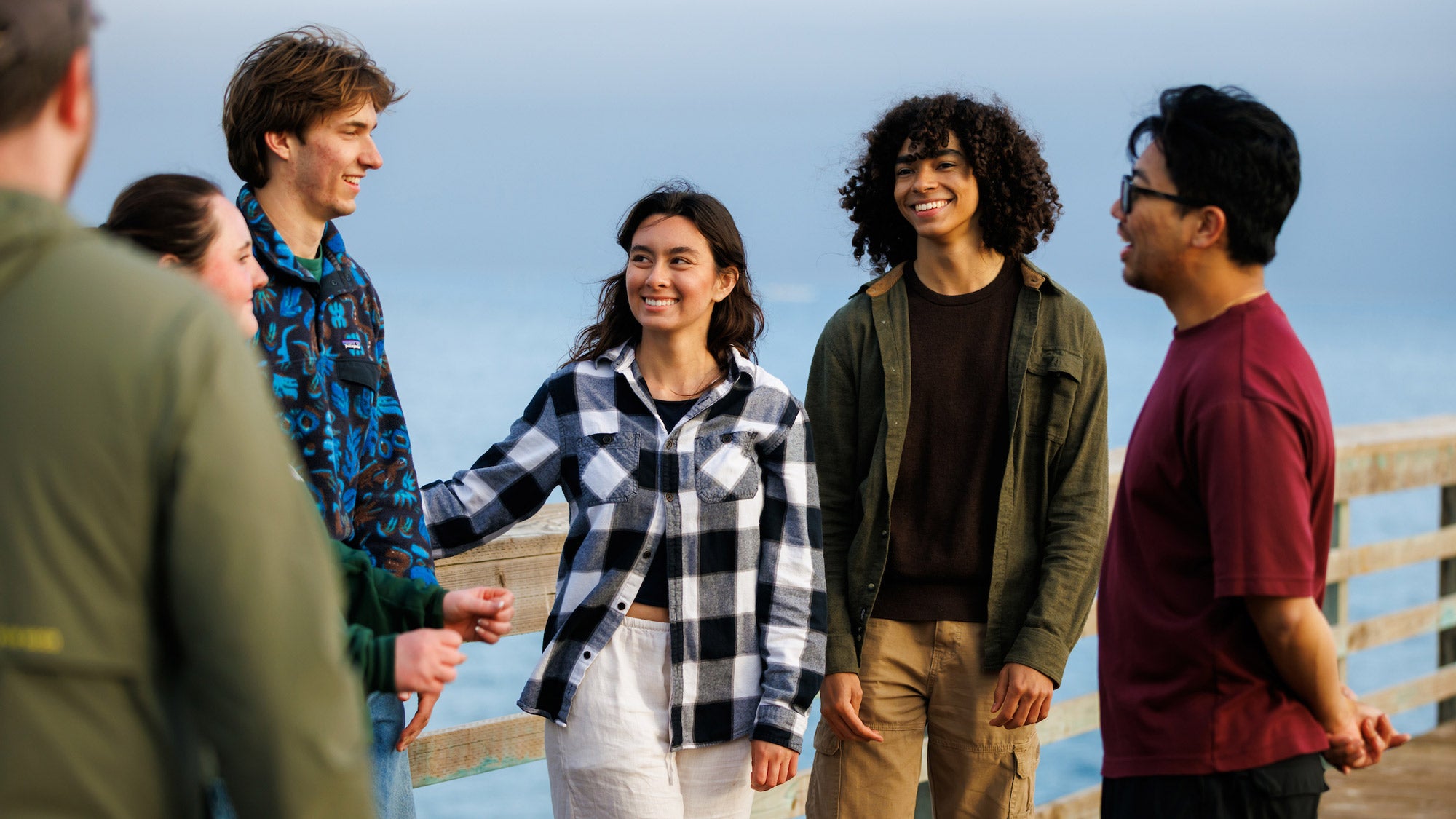 A group of Cal Poly students stand on a pier over the ocean