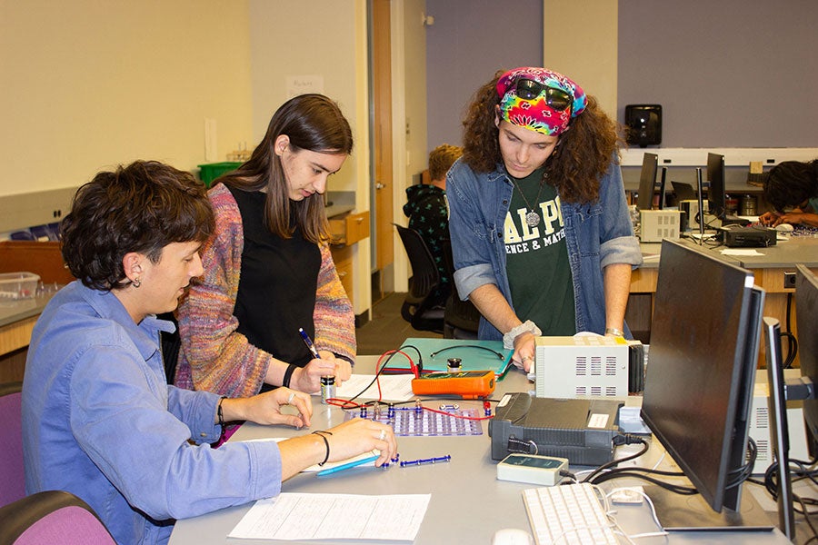 Learning Assistant Zachary Yockey helps students during a lab focused on a conceptual lesson on electrical currents.