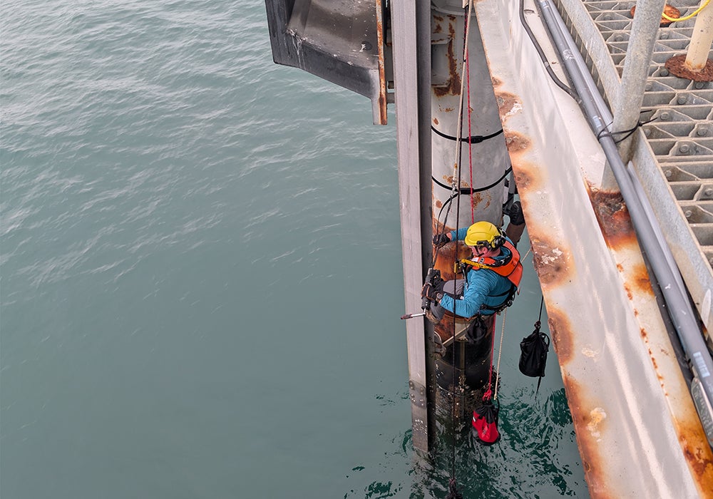 Connor Healy installs equipment at the Cal Poly Pier.