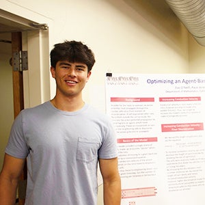 Math major Paco Jones poses in front of his research poster