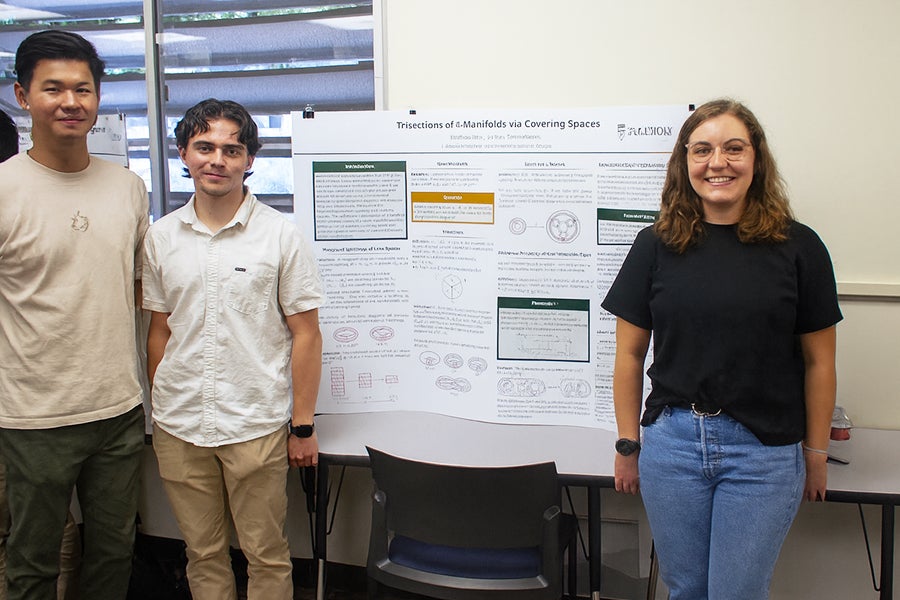 Math majors Tri Tran and Matthew Stark pose in front of their poster with Frost Postdoctoral Fellow Terrin Warren