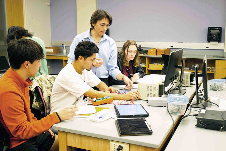 Physics Learning Assistant Seann Brick assists students in a physics lab.