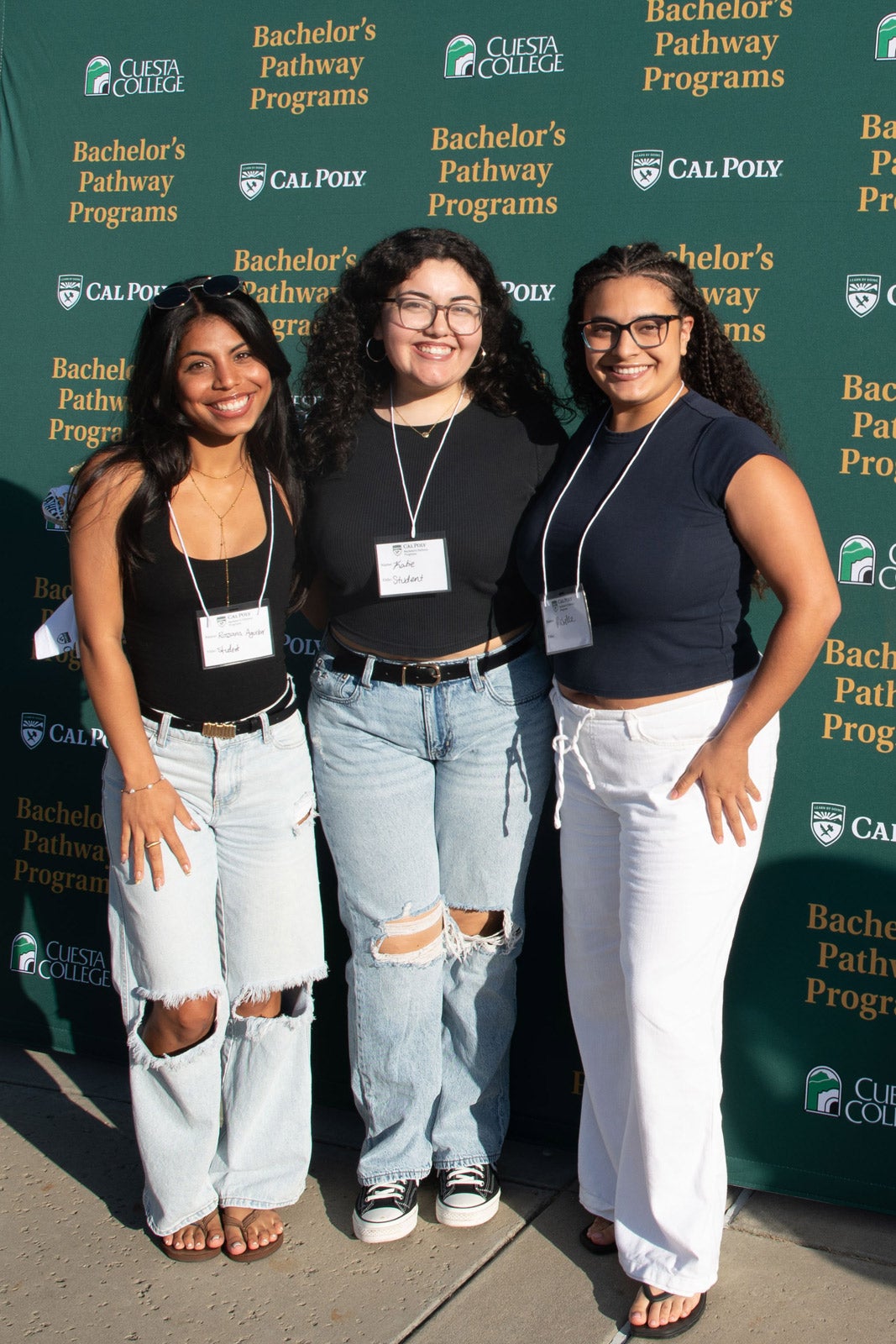 Three students pose in front of a Cuesta College and Cal Poly-branded backdrop that reads "Bachelor's Pathway Programs"