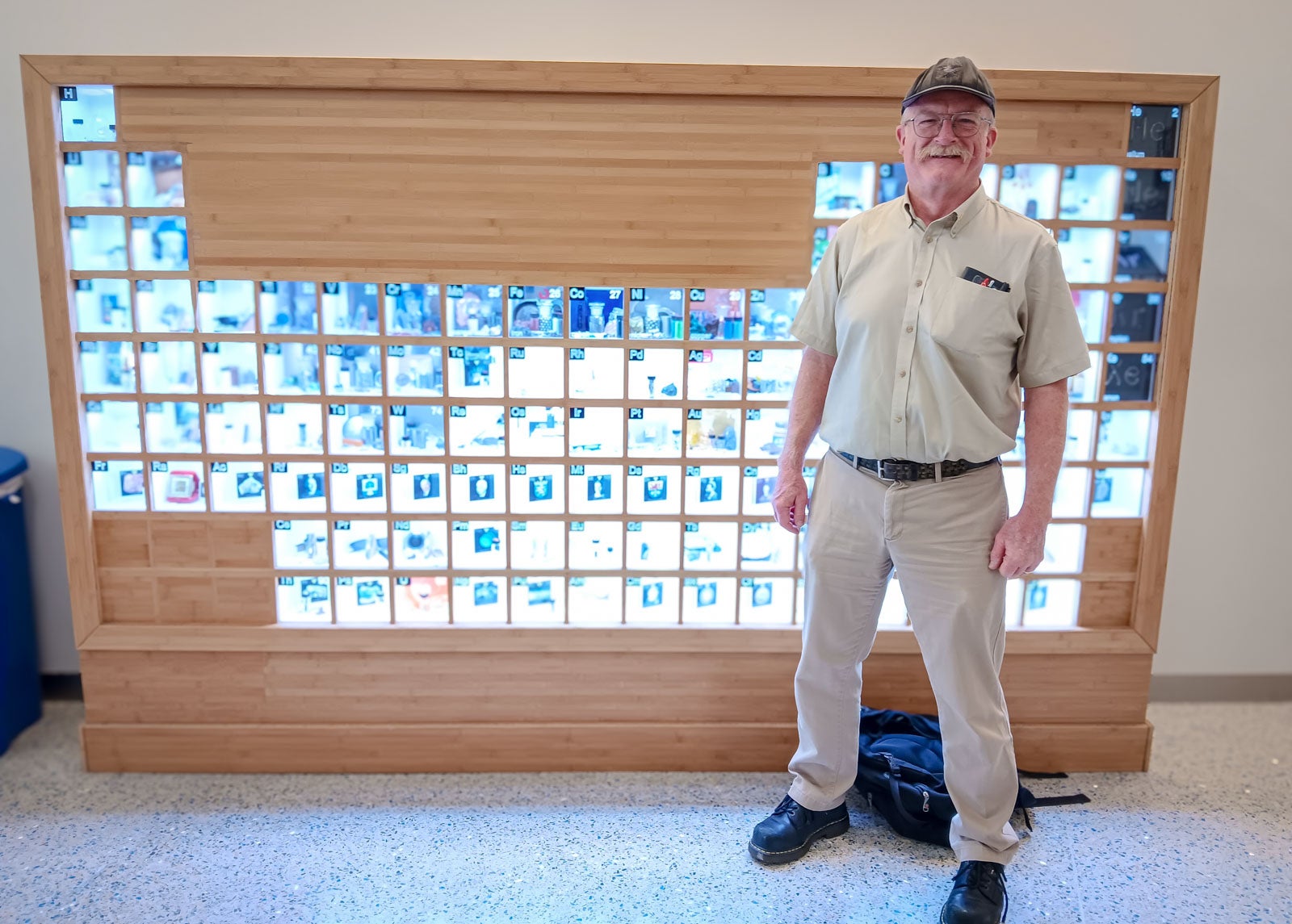 Mark Kent poses in front of the periodic table housed in the Baker Center