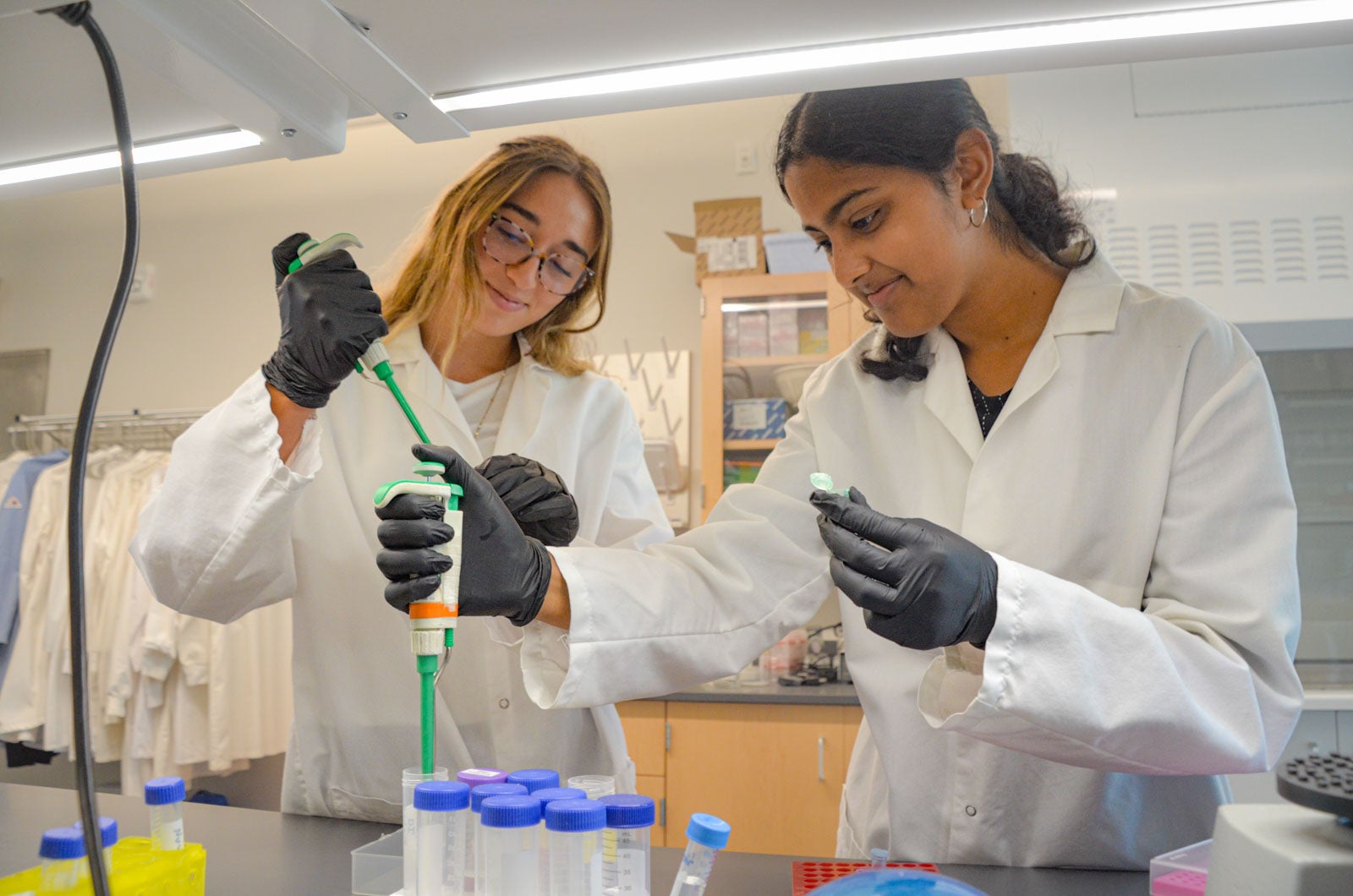 Two Sarepta Scholars conduct lab work using a workstation gifted by Sarepta Therapeutics to Cal Poly.