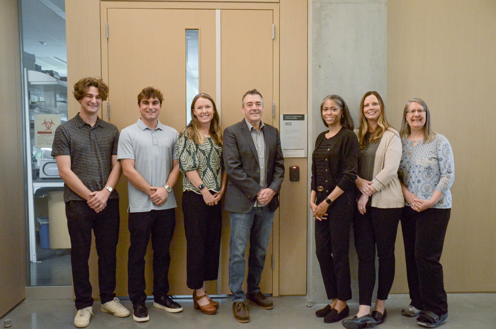 Sarepta Scholars pose with researchers from Sarepta Therapeutics in front of a lab on the Cal Poly campus.