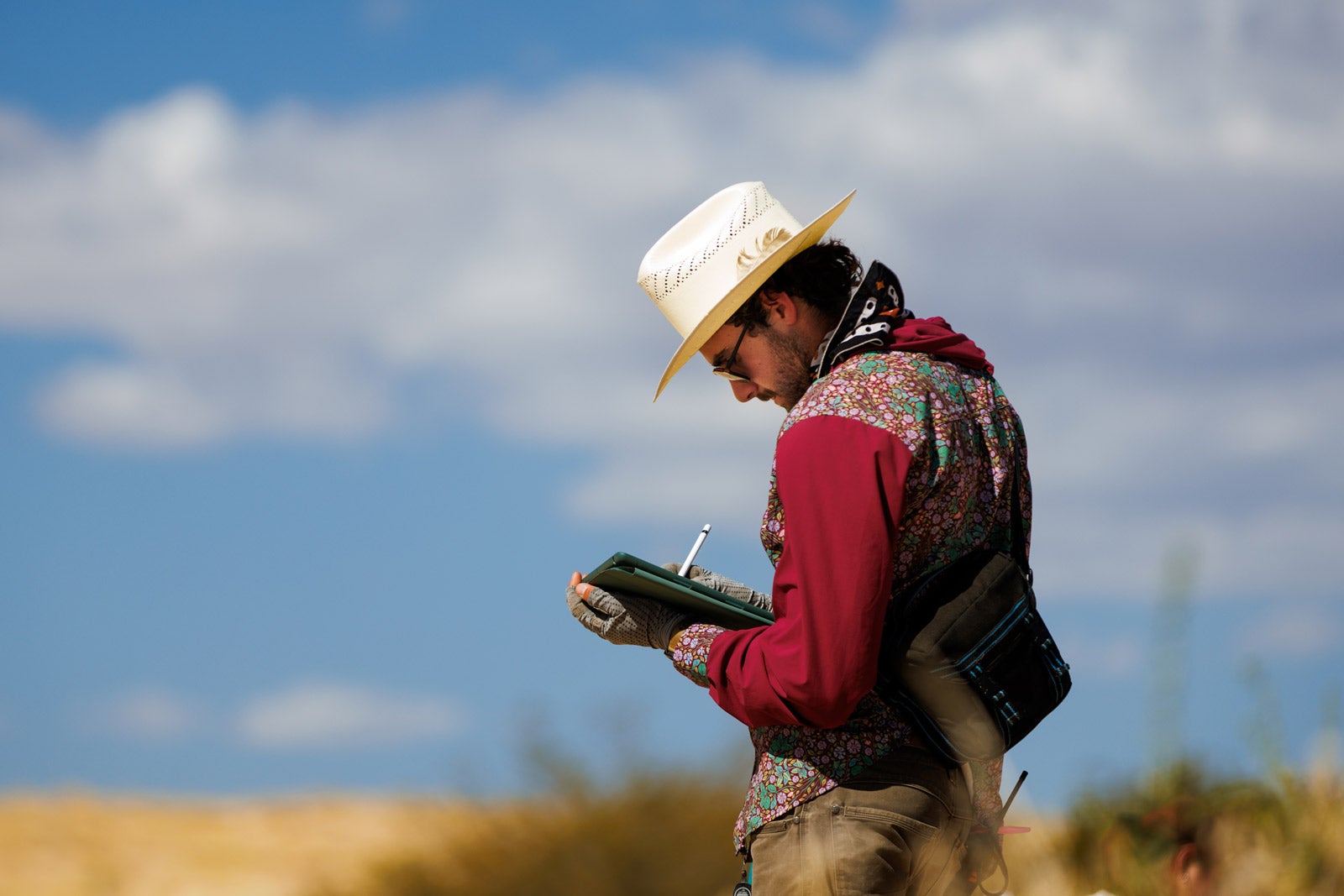 A student stands in a field taking notes