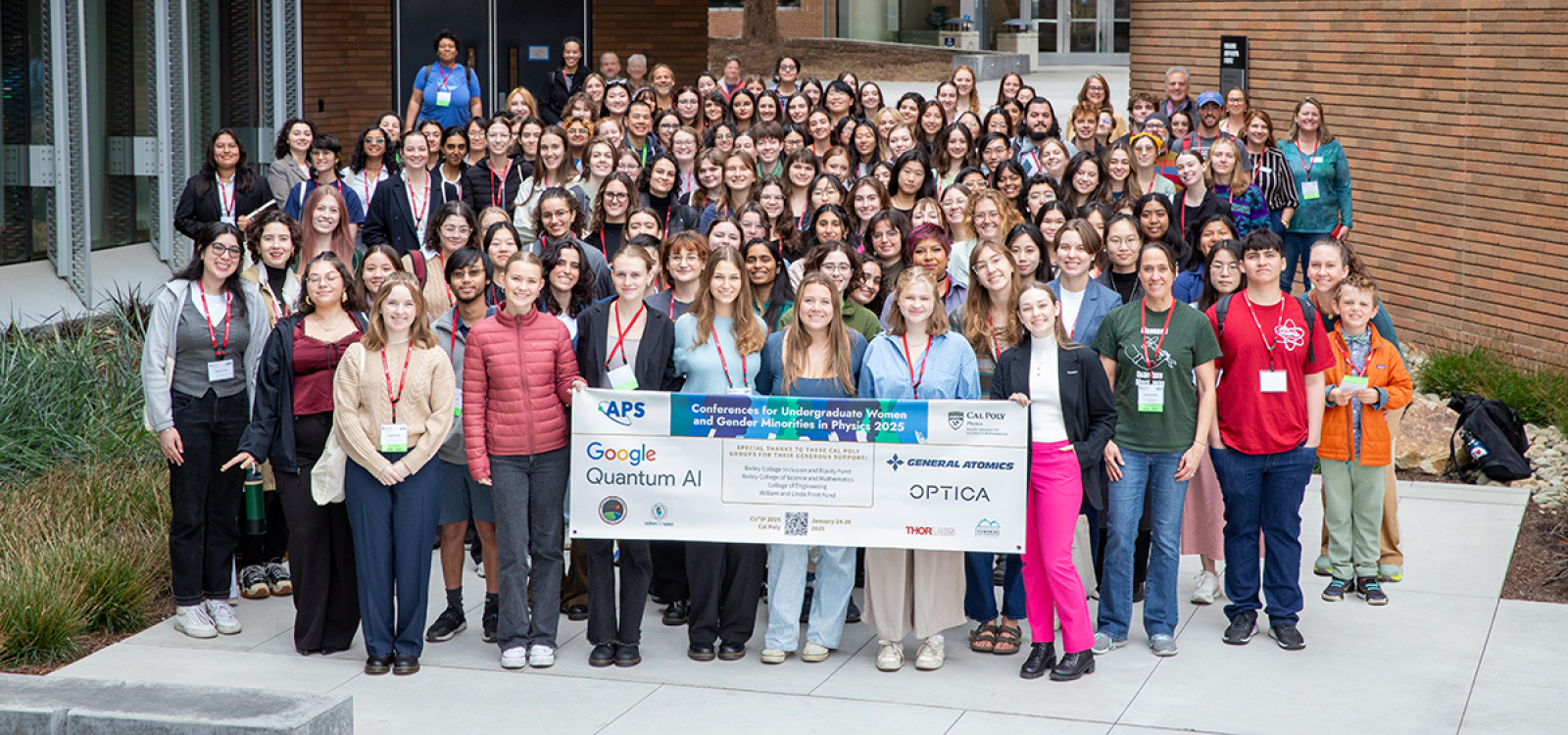 Participants in the 2025 APS Conference for Undergraduate Women and Gender Minorities in Physics gather for a group photo at Cal Poly, holding a conference banner.