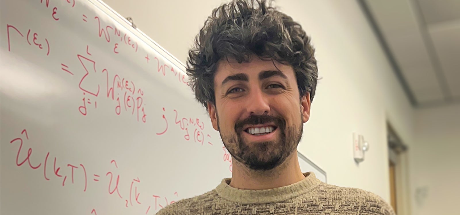 Physics faculty Ian Powell in front of white board.