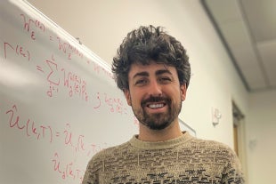 Physics faculty Ian Powell in front of white board.