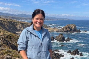 Marine science student Emma Riley poses in front of the rugged California coastline