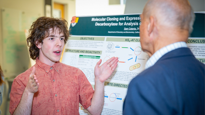 Biochemistry major Frost Research Scholar Sam Catania discusses his research with an alumnus.