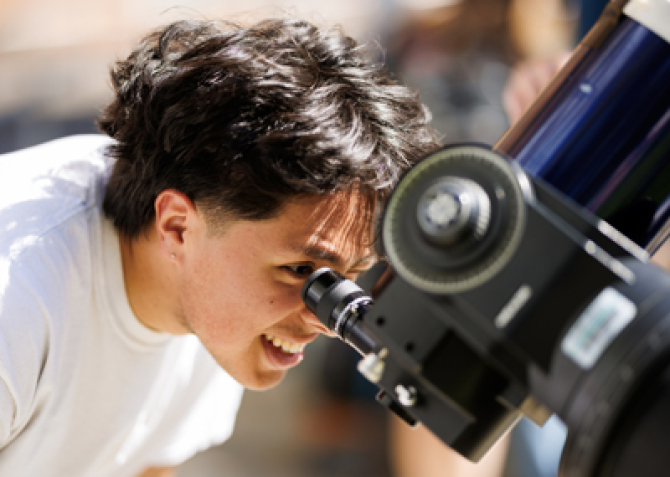 Student looks through a telescope