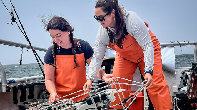 Marine science student working with mentor on a boat.
