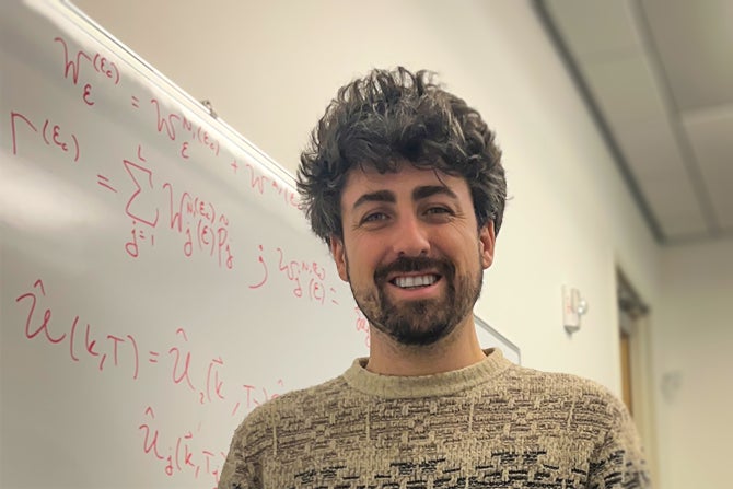 Physics faculty Ian Powell in front of white board.