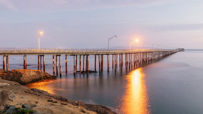 View of the Cal Poly Pier from land at sunset.
